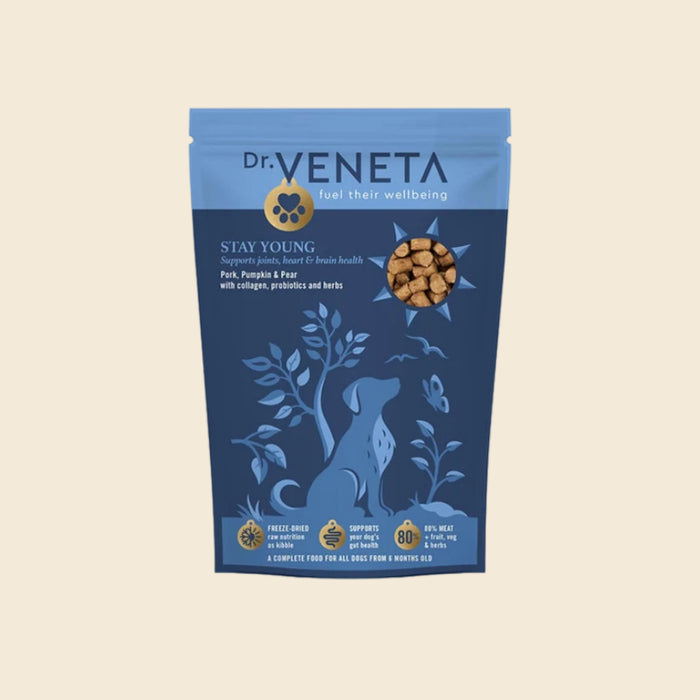 A stand-up pouch of Dr. Veneta Stay Young dog food, featuring a blue and navy design with a dog silhouette and a circular image of the kibble, set against a solid beige background.