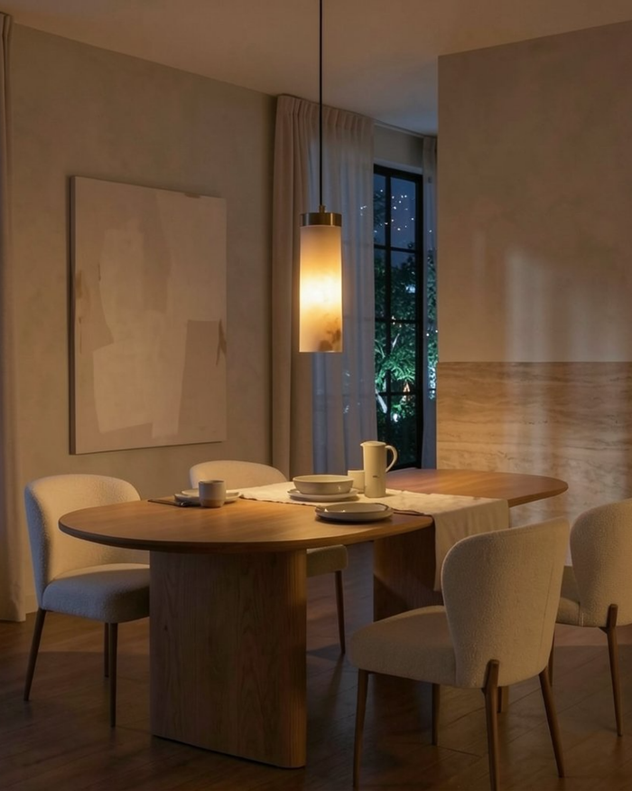 Dining room with a round wooden table and chairs, softly lit by a pendant light.