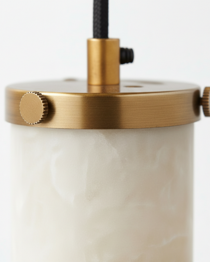 Close-up of a cylindrical light fixture with brass top and white base