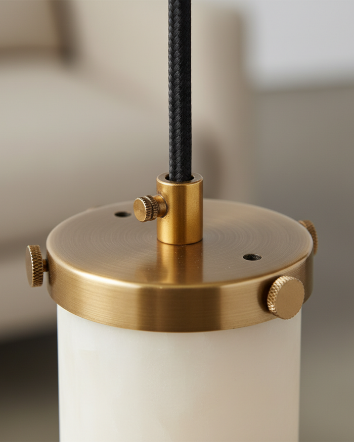 Close-up of a lamp with brass fitting and white base against a neutral background