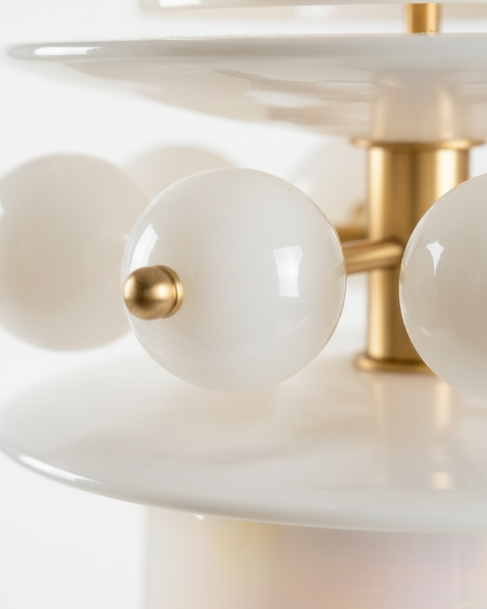 Close-up of a ceiling light fixture with white glass shades and gold accents.