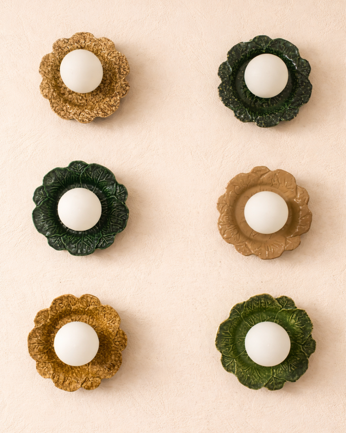 Decorative wall light with spherical elements in green and gold on a beige background