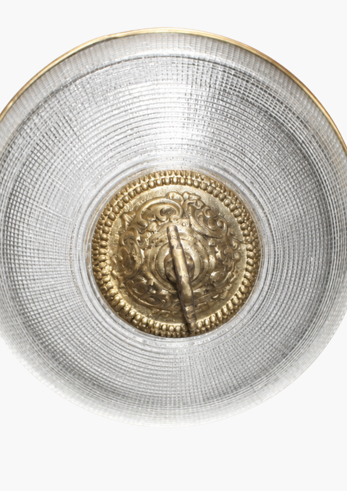 Textured glass globe pendant with handcrafted brass ornamental detailing. Gold coin encased in a silver holder on a white background