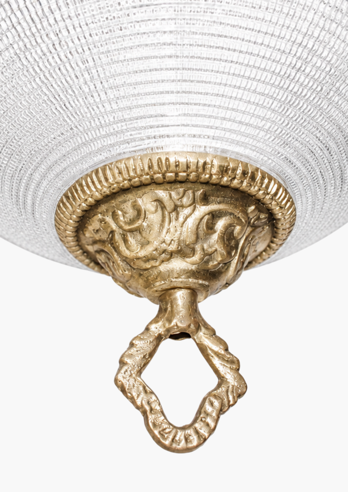 Textured glass globe pendant with handcrafted brass ornamental detailing. Decorative ceiling light fixture with intricate design and white lampshade.